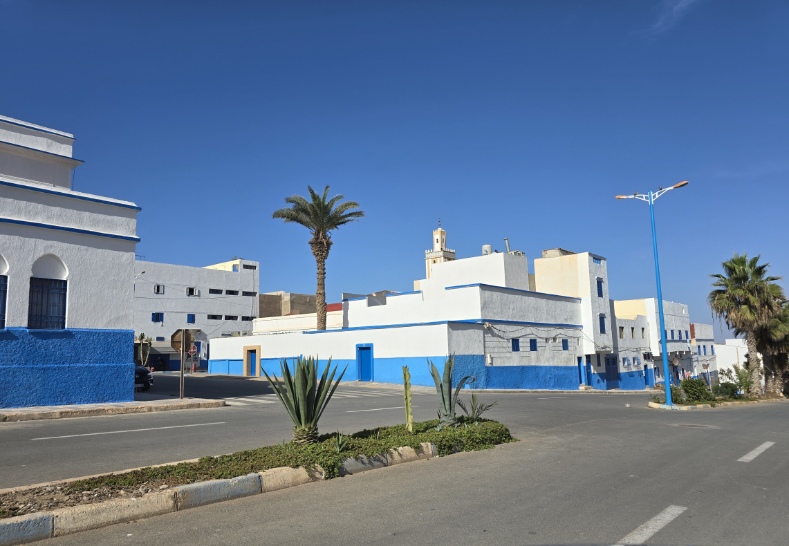 Vue actuelle de la rue · architecture blanche et bleue de Sidi Ifni dans un environnement résidentiel établi.